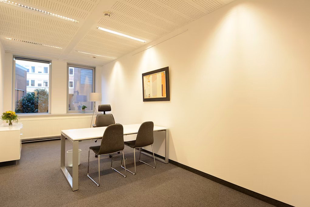 Helles Büro mit Schreibtisch und Besucherstühlen